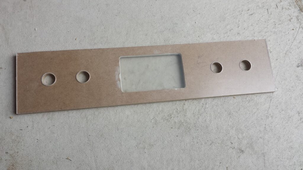 Arcade administration panel with four button holes drilled, and an opening cut out for a screen.  It is undecorated MDF.  Plexiglass covers the material.