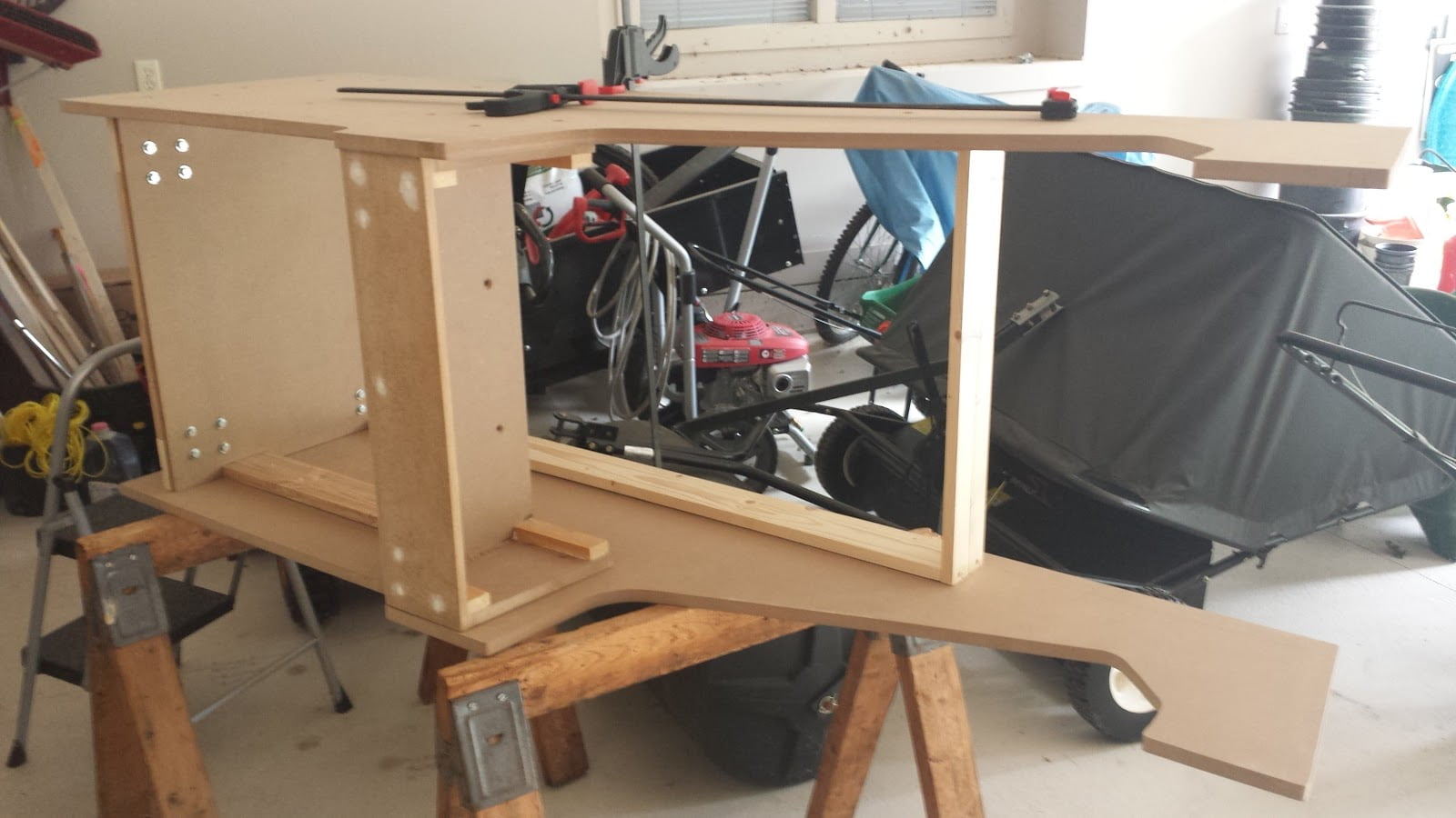 Partially-assembled arcade cabinet, lying on its side on a pair of sawhorses