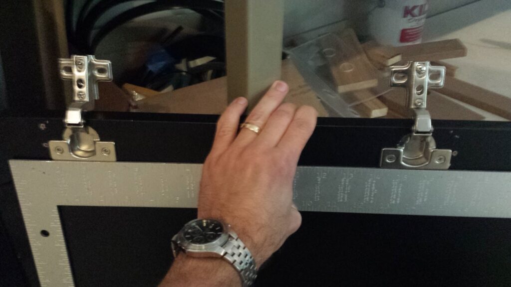 Using a straight-edge to ensure that a pair of Euro hinges are being installed in proper alignment