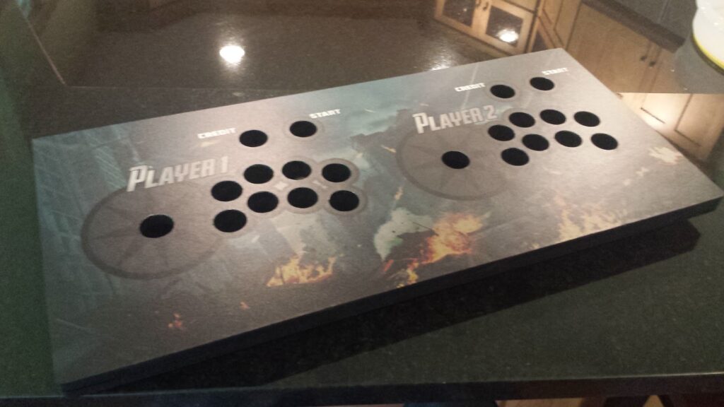 Control panel lying on a granite countertop.  All of the button & joystick holes have been cut away.