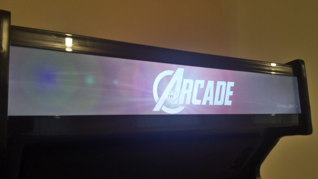Lit arcade marquee.  Text on the marquee reads "The Arcade", with the "A" styled like the "A" in the Avengers logo.