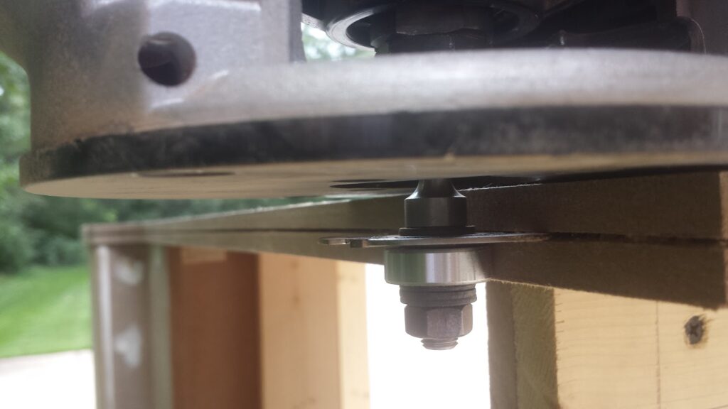 Close-up view of using a handheld router to cut a T-molding slot in an arcade panel side panel.