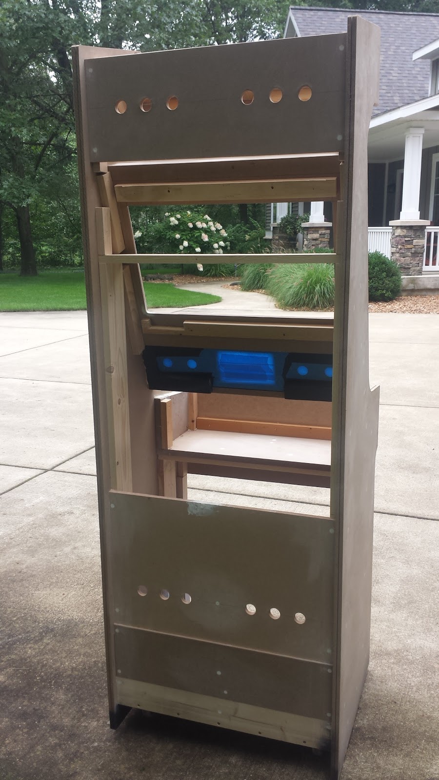 Rear view of a partly-assembled arcade cabinet.  The cabinet is primed with white primer, and has 12 small ventilation holes drilled into it 